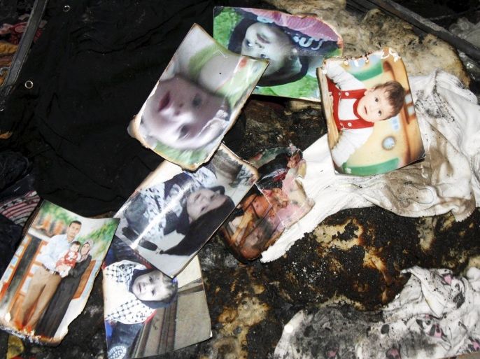 A picture of 18-month-old Palestinian baby Ali Dawabsheh (top L), who was killed after his family's house was set to fire in a suspected attack by Jewish extremists, is seen with other pictures of his family as they are collected by a relative at the burnt house in Duma village near the West Bank city of Nablus July 31, 2015. Suspected Jewish extremists set fire to a Palestinian home in the occupied West Bank on Friday, killing Dawabsheh and seriously injuring several other family members, an act that Israel's prime minister described as terrorism. REUTERS/Abed Omar Qusini