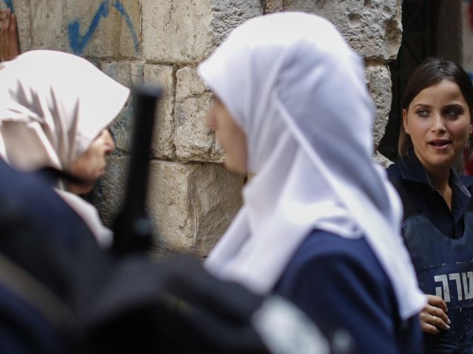 An Israeli female police officer (R) guarding near an entrance of the Al-Aqsa Mosque watches Muslim women passing by in the Old City of Jerusalem, 02 August 2015. Israeli police reports said 02 August that a minor riot broke out between Muslim and Jewish visitors to the Al-Aqsa compound earlier in the same day's morning.