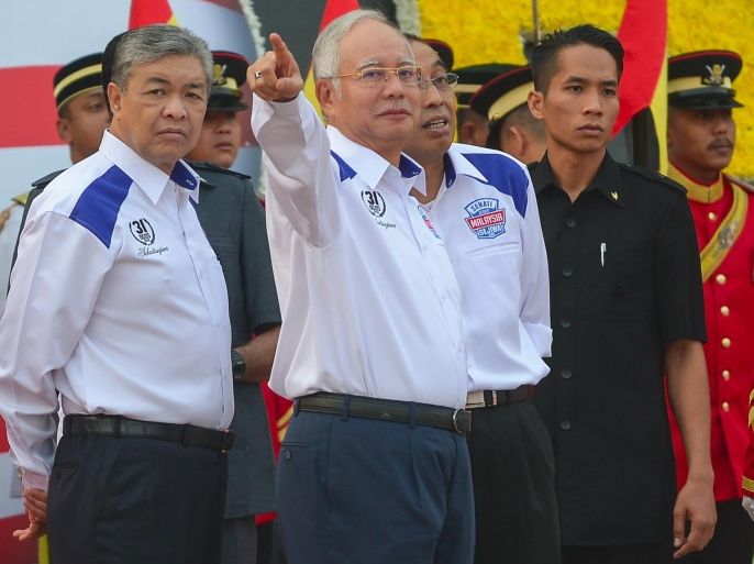 Malaysia's Prime Minister Najib Razak (C) gestures as his deputy, Ahmad Zahid Hamidi (L), looks on before the start of National Day celebrations at Independence Square in Kuala Lumpur on August 31, 2015. Malaysia's government reclaimed the streets of the capital on August 31 after massive weekend protests demanding the premier's ouster, staging its own show of force with colourful National Day celebrations attended by thousands.     AFP PHOTO / MOHD RASFAN