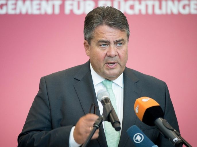 German vice chancellor Sigmar Gabriel speaks at an event to honor, volunteer helpers for refugees , in Berlin, Saturday Aug. 29, 2015. Words in background read : Commitment for Refugees. ( Kay Nietfeld/dpa via AP)