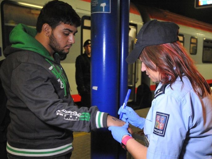In this Sept. 1, 2015 picture a Czech police officer marks a refugee with a number while detaining more than 200 refugees, mostly from Syria, on trains from Hungary and Austria at the railway station in Breclav, Czech Republic. (AP Photo, CTK/Igor Zehl) SLOVAKIA OUT