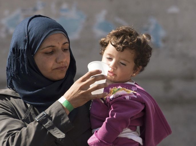 A migrant gives water to her child outside the main railway station in Munich, Germany, September 1, 2015. The German government expects that between 240,000 and 460,000 extra people will be entitled to social benefits next year due to the influx of refugees and migrants, Labour Minister Andrea Nahles said on Tuesday. REUTERS/Lukas Barth