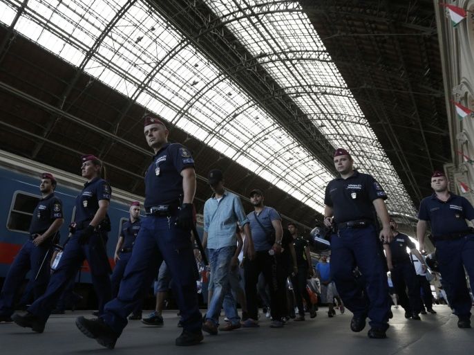 A group of migrants is escorted by Hungarian police officers onto a train which will transport them to one of Hungary's migrant and refugee camps from the Keleti Railway Station, after police stopped them from getting on trains to Germany, in Budapest, Hungary, Wednesday, Sept. 2, 2015. Over 150,000 migrants have reached Hungary this year, most coming through the southern border with Serbia. Many apply for asylum but quickly try to leave for richer EU countries. (AP Photo/Petr David Josek)