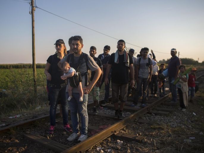In this Tuesday, Sept. 1, 2015, photo, Syrian refugees walk across railways tracks next to the Serbian town of Horgos to cross the border and enter Hungary. Over 150,000 migrants have reached Hungary this year, most coming through the southern border with Serbia. Many apply for asylum but quickly try to leave for richer EU countries. (AP Photo/Santi Palacios)