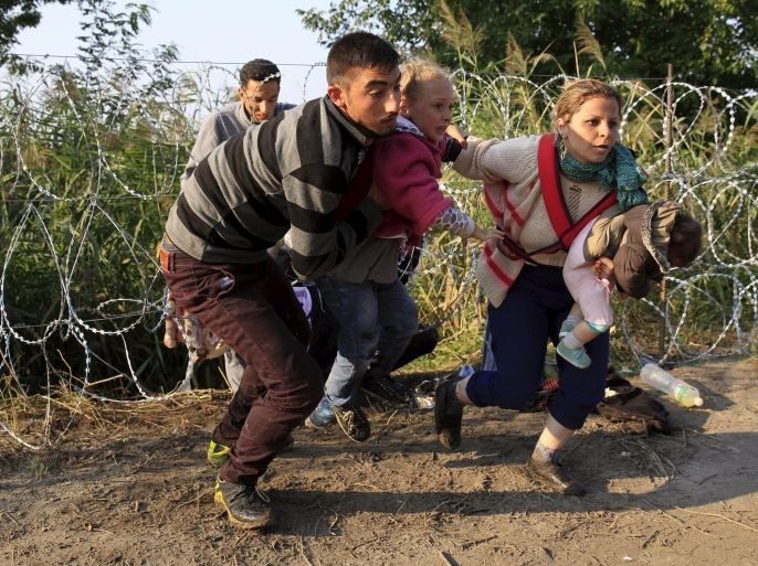 Syrian migrants run after crossing under a fence as they enter Hungary, at the border with Serbia, near Roszke, August 27, 2015. Hungary made plans on Wednesday to reinforce its southern border with helicopters, mounted police and dogs, and was also considering using the army as record numbers of migrants, many of them Syrian refugees, passed through coils of razor-wire into Europe. REUTERS/Bernadett Szabo
