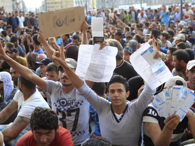 Refugees raise their documents and railways tickets outside the Keleti station in Budapest, Hungary September 2, 2015. Hundreds of migrants protest in front of Budapest's Keleti Railway Terminus for a second straight day on Wednesday, shouting "Freedom, freedom!" and demanding to be let onto trains bound for Germany from a station that has been closed to them by Hungarian riot police officers. REUTERS/Bernadett Szabo