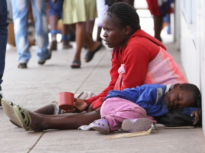A blind woman begs for money while her child sleeps next to her on the streets of Harare, Zimbabwe, Thursday, Dec. 5, 2013. According to the latest independent surveys in Zimbabwe the gap between the rich and poor continues to grow. The recent elections in the country have done little to deal with the challenges facing a nation trying to recover from an economic meltdown and the ravages of hyperinflation. (AP Photo/Tsvangirayi Mukwazhi)