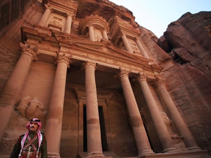 In this Thursday, March 6, 2014 photo, a Bedouin Jordanian guard stands in front of Al Khazneh, Arabic for the Treasury, the most dramatic of many facades carved into the mountains, in the ancient city of Petra, Jordan. The kingdom has launched an ecotourism project with the establishment of three camps in the Petra region, the first of 22 proposed eco-camps that will eventually link three areas in Jordan including the Dana Biosphere Reserve located in south-central Jordan. (AP Photo/Mohammad Hannon)
