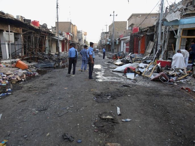 Iraqi policemen stand guard as shop owners clean up debris and inspect the aftermath of a deadly car bomb explosion in a busy commercial district of al-Zubair, a suburb of the predominantly Shiite city of Basra, 340 miles (550 kilometers) southeast of Baghdad, Iraq, Tuesday, Oct. 6, 2015. Iraqi officials say a series of car bombings across Iraq Monday killed and wounded dozens of people. The Islamic State group has claimed responsibility for the car bombing in al-Zubair that killed at least 10 people on Monday. (AP Photo/Nabil al-Jourani)