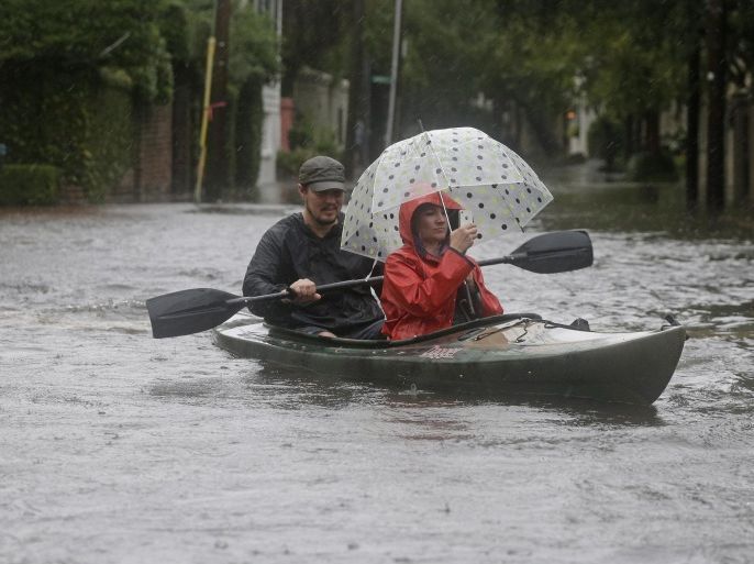 Paul Banker, left, paddles a kayak and his wife Wink Banker, right, takes photos on a flooded street in Charleston, S.C., Saturday, Oct. 3, 2015. A flash flood warning was in effect in parts of South Carolina, where authorities shut down the Charleston peninsula to motorists. (AP Photo/Chuck Burton)