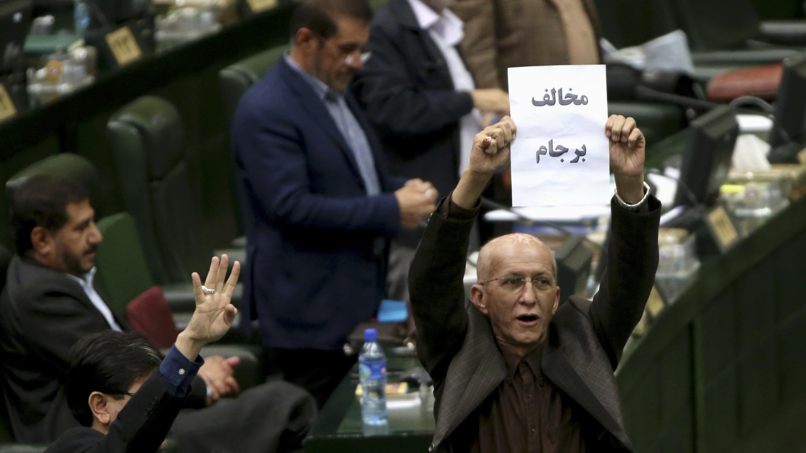 ‪برلماني إيراني يرفع ورقة للتعبير عن رفضه الاتفاق النووي مع القوى الكبرى‬ (أسوشيتد برس)