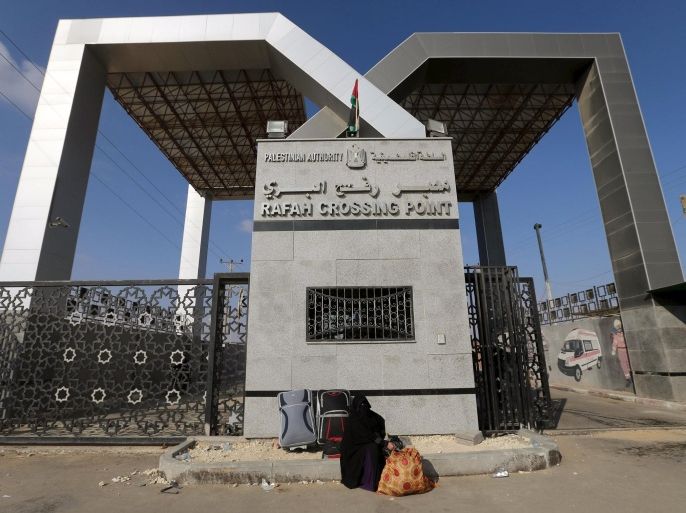 A Palestinian woman sits in front of the gate of Rafah border crossing as she waits for a travel permit to cross into Egypt, in Rafah in the southern Gaza Strip June 14, 2015. Egypt opened the Rafah border crossing on Saturday to allow Palestinians to travel in and out of the Gaza Strip for the first time in three months, in a possible sign of easing tension between Cairo and Gaza's dominant Islamist Hamas movement. Gaza, a small impoverished coastal enclave, is under blockade by neighbouring Israel, and Egypt has kept its Rafah crossing largely shut since Cairo's Islamist president was toppled by the army in 2013. REUTERS/Ibraheem Abu Mustafa