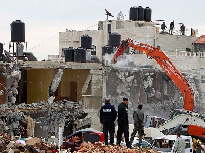israeli police officers look as an excavator demolishes a house in the east jerusalem neighbourhood of beit hanina february 5, 2013. a statement from the jerusalem municipality said there was a court order for the demolition of the house, which was built without a permit in an open landscape area where construction is forbidden. reuters/ammar awad (jerusalem - tags: politics civil unrest business construction) (رويترز)