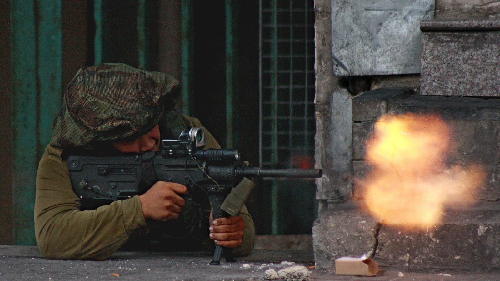 جندي إسرائيلي يصوب رصاص بندقيته تجاه متظاهرين في الخليل (الأوروبية)