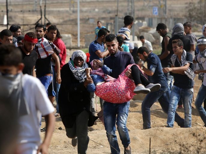 A Palestinian protester is evacuated by comrades after being injured by a tear gas canister during clashes with Israeli security forces near the Nahal Oz border crossing with Israel, east of Gaza City on October 10, 2015. Violence between Israelis and Palestinians threatened to spiral out of control after unrest spread to Gaza, the Palestinian death toll rose and a new stabbing by a 16-year-old in Jerusalem. AFP PHOTO / MAHMUD
