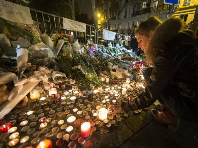 People place flowers and light candles in tribute for the victims of the 13 November Paris attacks near the Bataclan concert venue in Paris, France, 14 November 2015. At least 129 people were killed in a series of attacks in Paris on 13 November, according to French officials.