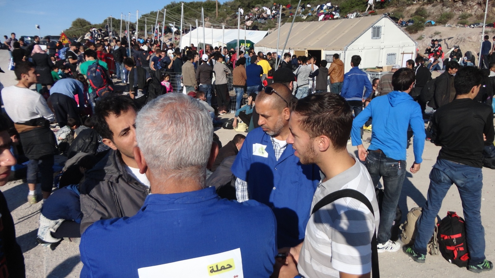 متطوعون أمام خيام نصبت لإيواء اللاجئين (الجزيرة)