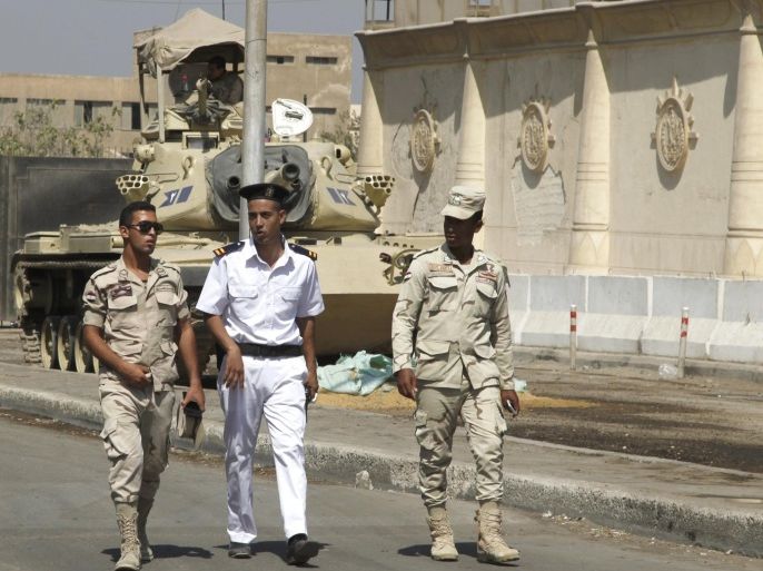 Police and army soldiers are seen in front of a tank as they guard outside Tora prison, where Al Jazeera television journalists Mohamed Fahmy and Baher Mohamed were held and are having their retrial, in Cairo, Egypt, July 30, 2015. A Cairo court session which had been expected to deliver a verdict on Thursday in the retrial of Al Jazeera television journalists has been adjourned, Al Jazeera said on its Twitter feed. The journalists are charged with aiding a terrorist organisation, a reference to the Muslim Brotherhood, which was outlawed in Egypt after the army ousted Islamist president Mohamed Mursi amid mass protests against his rule in 2013. REUTERS/Asmaa Waguih