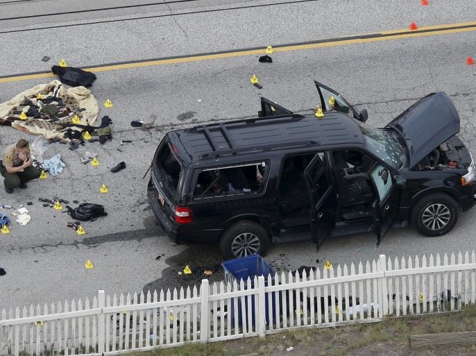 A law enforcement officer looks over the evidence near the remains of a SUV involved in the Wednesdays attack is shown in San Bernardino, California December 3, 2015. Authorities on Thursday were working to determine why a man and a woman opened fire at a holiday party of his co-workers in Southern California, killing 14 people and wounding 17 in an attack that appeared to have been planned. REUTERS/Mario Anzuoni