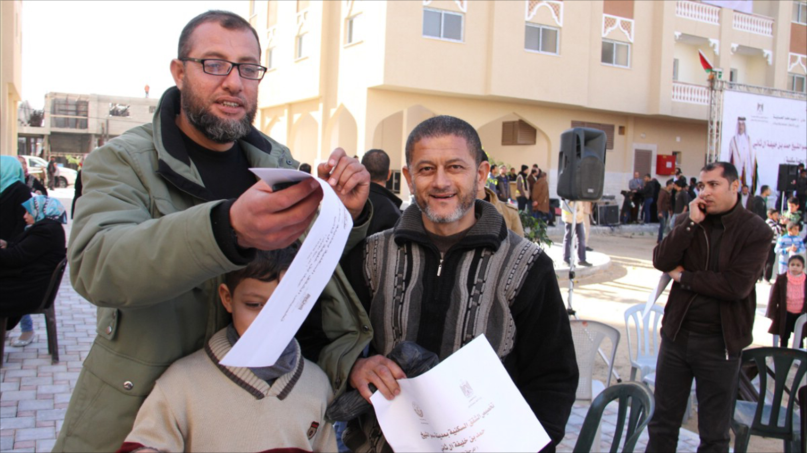‪المواطن سامي الشيخ عيد أحد المستفيدين من المدينة (يمين) ويبدو سعيدا بحصوله على كتاب التخصيص‬ (الجزيرة)
