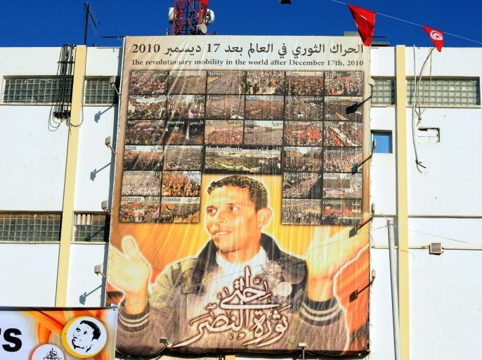 a giant portrait of tunisian protestor mohamed bouazizi hangs on the wall in the central town of sidi bouzid on december 17, 2013, as they celebrate the 3rd anniversary of the start of the revolution, the first of the arab spring uprisings, triggered by the self-immolation of bouazizi, the vegetable vendor harassed by poverty and police atrocity. tunisians gathered today at the birthplace of the arab spring to vent their anger at social exclusion three years
