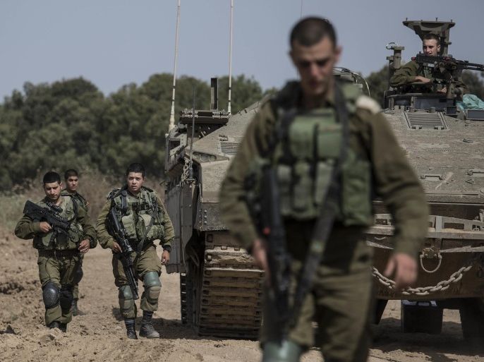 Israeli soldiers walk by a tank near the Israel Gaza border, Wednesday, May 4, 2016. The Israeli army says a tank has fired at a target in the northern Gaza Strip following an explosion on the Palestinian side of the border. The army says it's trying to determine the source of the explosion, which took place on Wednesday. Earlier, a tank fired into Gaza after a mortar shell was launched toward Israeli forces near the southern Gaza Strip. (AP photo/Tsafrir Abayov)