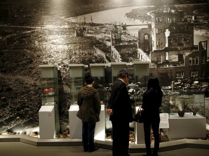 Visitors stand in front of a photograph showing Hiroshima city after the 1945 atomic bombing as they look at artifacts from the destruction caused by the bomb, at Hiroshima Peace Memorial Museum in Hiroshima, western Japan, March 26, 2015. A U.S. bomber dropped the atomic bomb on Hiroshima on August 6, 1945, killing about 140,000 by the end of the year, out of the 350,000 who lived in the city. The city still has some 60,000 survivors but their average age is approaching 80. Picture taken March 26, 2015. REUTERS/Issei Kato