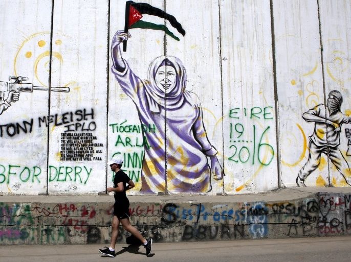epaselect epa05238935 A participant runs in front of murals on the controversial Israeli separation wall as running enthusiasts take part in the 'Right To Movement' Palestine Marathon 2016 run in the West Bank town of Bethlehem, 01 April 2016. Over 4,300 runners took part in marathon and shorter distance runs for the forth year in a row. The 'Right To Movement' describes themselves as a non-profit, non-religious and non-political global running community.