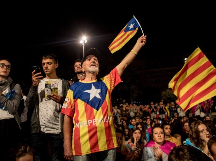 BARCELONA, SPAIN - OCTOBER 01: People hold Catalan flags as they listen to Catalan President Carles Puigdemont speak via a televised press conference as they await the result of the Indepenence Referendum at the Placa de Catalunya on October 1, 2017 in Barcelona, Spain. More than five million eligible Catalan voters are estimated to visit 2,315 polling stations today for Catalonia's referendum on independence from Spain. The Spanish government in Madrid has declared