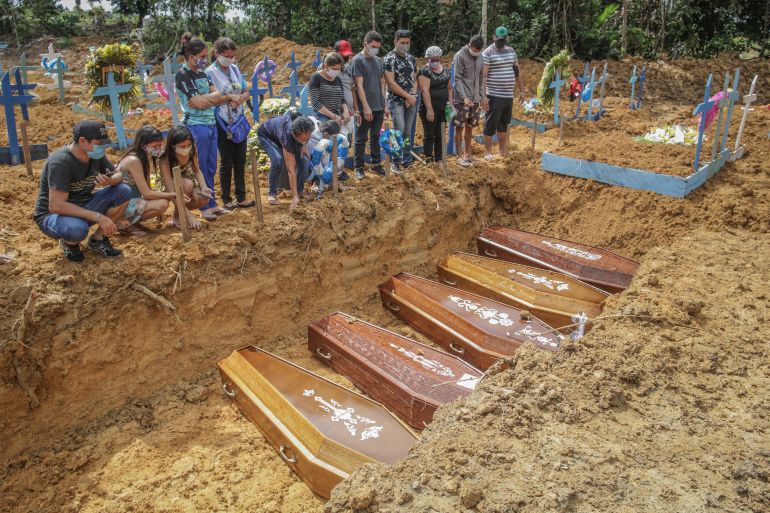 MANAUS, BRAZIL - MAY 19: People wearing protective masks observe to the graves with the remains of their relatives during a mass burial of coronavirus (COVID-19) pandemic victims at the Parque Taruma cemetery on May 19, 2020 in Manaus, Brazil. Brazil has over 260,000 confirmed cases and more than 17,000 deaths caused by coronavirus (COVID-19) pandemic. (Photo by Andre Coelho/Getty Images)