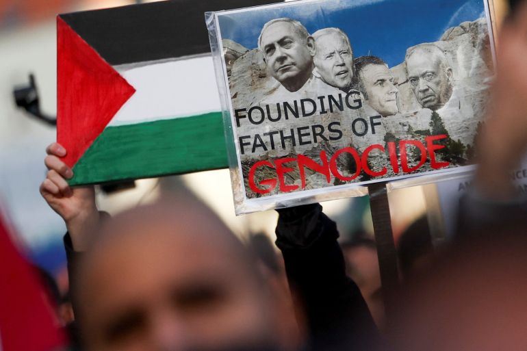 A demonstrator holds a placard depicting Israeli Prime Minister Benjamin Netanyahu, U.S. President Joe Biden, French President Emmanuel Macron and Israeli Defense Minister Yoav Gallant during a protest in support of Palestinians in Gaza, as the conflict between Israel and Palestinian Islamist group Hamas continues, in Brussels, Belgium, November 11, 2023. REUTERS/Yves Herman