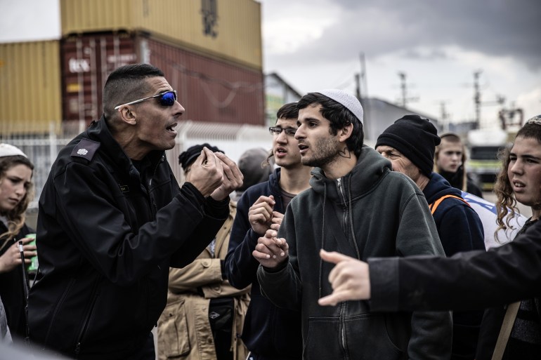 ASHDOD, ISRAEL - FEBRUARY 01: A police officers argues with a group of Jewish, called 'Hill Youth' gather to stage a demonstration to prevent humanitarian aid being sent to Gaza near the port in Ashdod, Israel on February 01, 2024. (Photo by Mostafa Alkharouf/Anadolu via Getty Images)