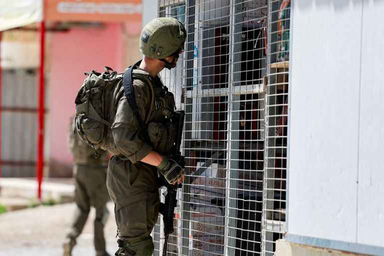 A member of the Israeli army inspects the scene of a shooting incident, near Jericho in the Israeli-occupied West Bank, March 28, 2024. REUTERS/Ammar Awad