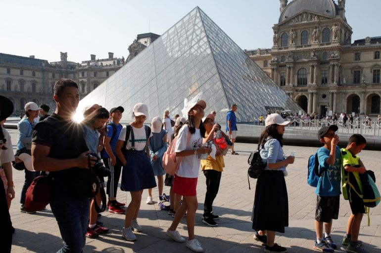 Chinese tourists stand in front of the Louvre Pyramid designed by Chinese-born U.S. Architect Ieoh Ming Pei outside the Louvre Museum in Paris, France, July 26, 2018. Picture taken July 26, 2018. REUTERS/Philippe Wojazer