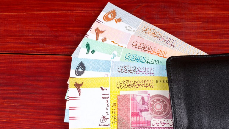 Money from Sudan in the black wallet on a wooden background