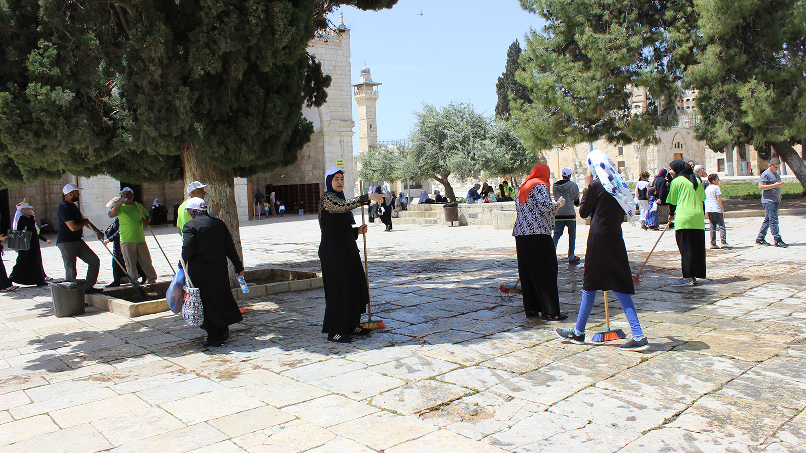 نساء مشاركات بالمعسكر ينظفن الساحة الأمامية للمصلى القبلي (الجزيرة)