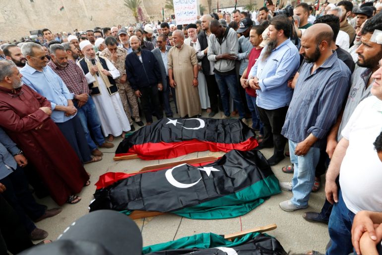 People pray near coffins draped with Libyan flags, with the bodies of members of the Libyan internationally recognised government forces who were killed during clashes, during a funeral in Tripoli, Libya April 24, 2019. REUTERS/Ismail Zitouny