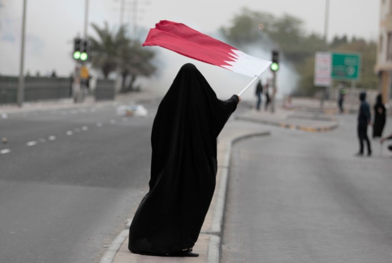 Female protester waves Bahrain's flag as she takes part in a protest marking the 4th anniversary of the 14th February uprising to demand democratic reforms in the village of Sanabis
