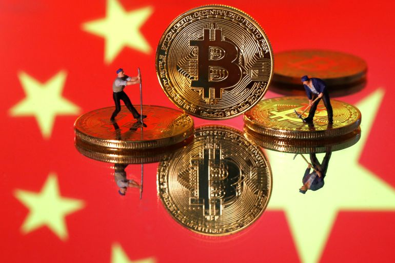Picture illustration of small toy figurines and representations of the Bitcoin virtual currency displayed in front of an image of China's flag