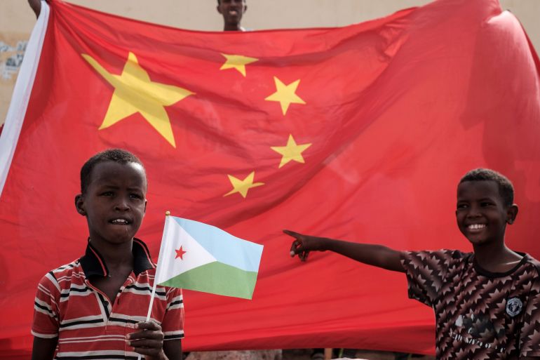 A boy holds Djiboutian national flag in front of Chinese national flag as he waits for Djibouti's President Ismail Omar Guellehas before the launching ceremony of new 1000-unit housing contruction project in Djibouti, on July 4, 2018. The new 1000-unit construction project by the Ismail Omar Guelleh Foundation for Housing is financially supported by China Merchant, the operation parther of newly inaugurated Djibouti International Free Trade Zone (DITTZ) with Djibouti Ports and Free Zones