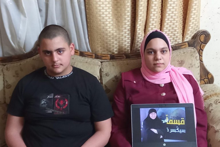 Yaqeen Abu Safaqah et son frère tenant une photo de leur mère, la prisonnière Zahra Khadrj - Cisjordanie - Qalqilya - Maison de la famille de la prisonnière Zahra Khadrj - Al Jazeera Net