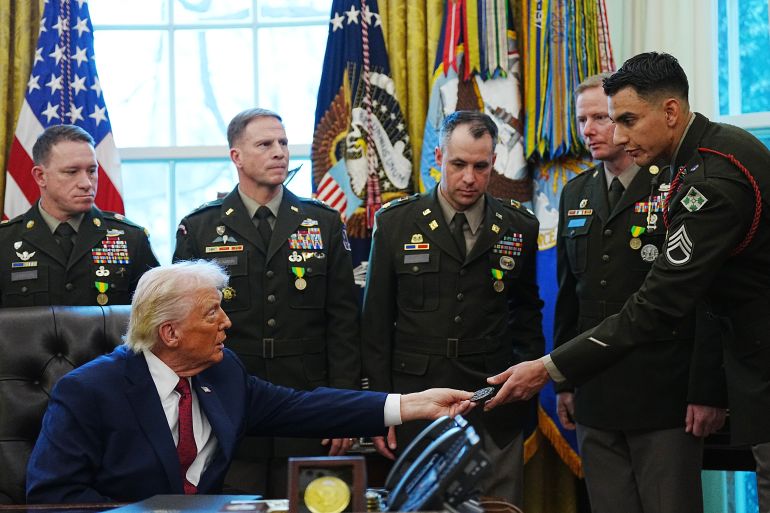 epa12595020 US President Donald Trump (L) gives away Presidential Challenge Coins as he speaks about his border policies during a Mexican Border Defense Medal (MBDM) presentation in the Oval office of the White House, in Washington, DC, USA, 15 December 2025. The MBDM medal was established by a memorandum from the Department of Defense in August 2025, to be awarded to service members for their deployment and work on the southern border. EPA/BONNIE CASH / POOL